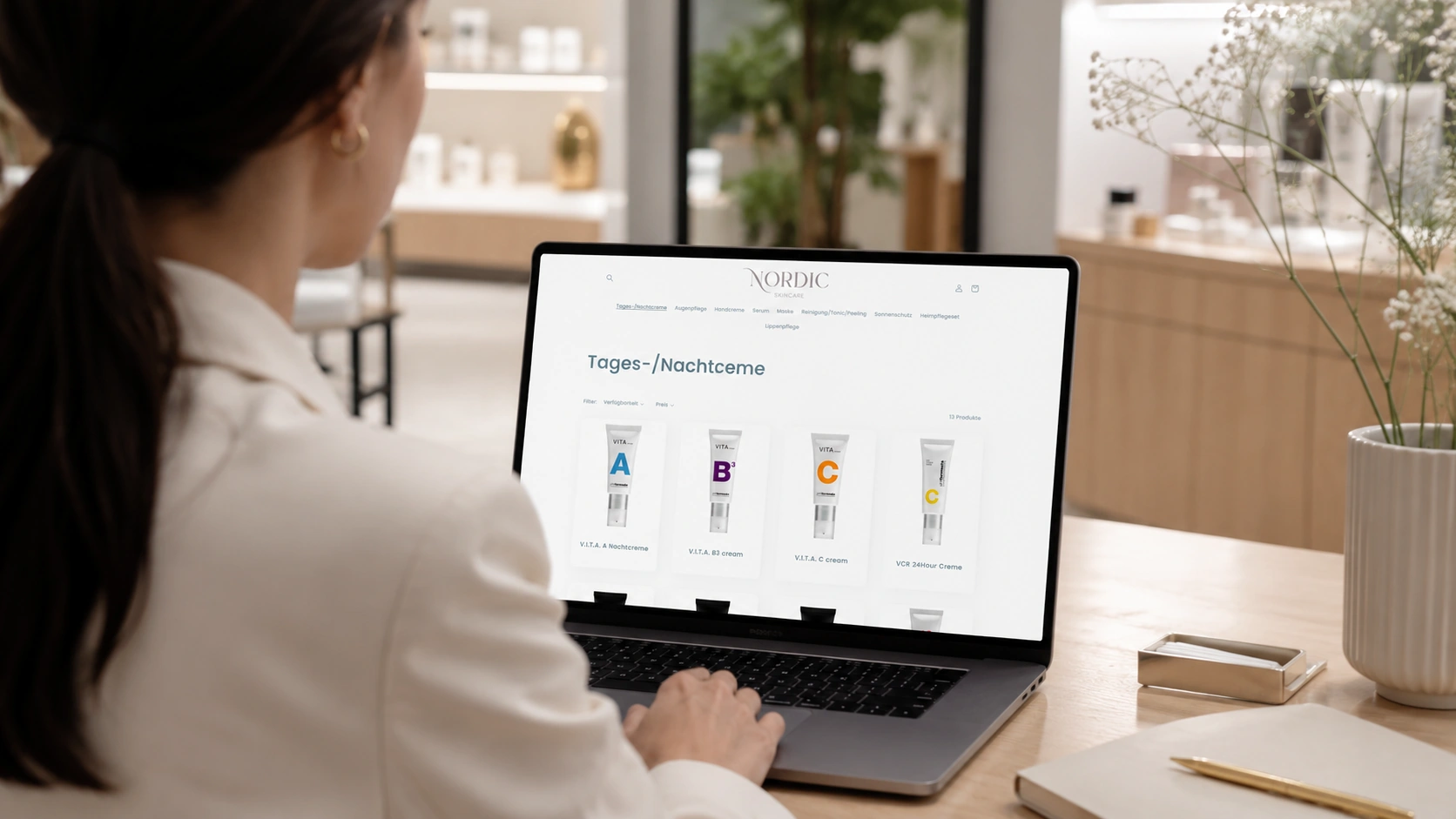 Frau im Nordic Skincare Store Luzern betrachtet den eigenen Online-Shop mit V.I.T.A.-Pflegeprodukten auf einem MacBook